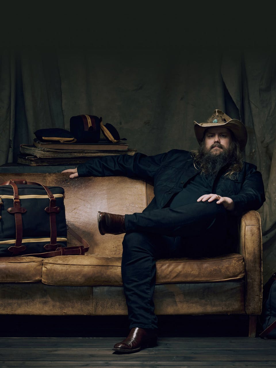 Chris Stapleton sitting on a couch with Filson luggage